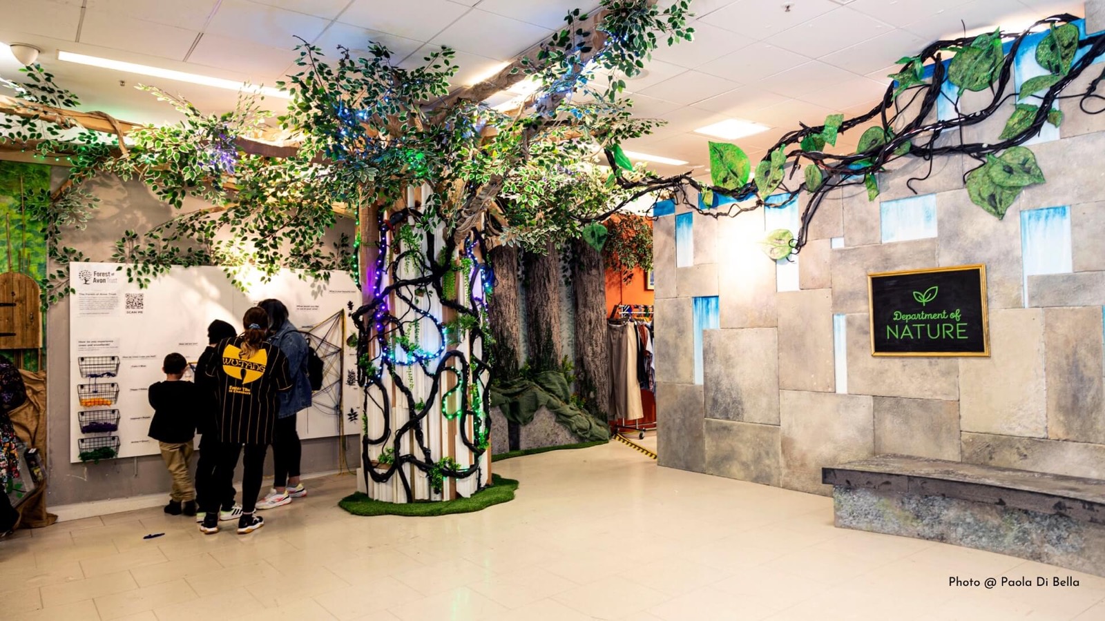 Des visiteurs marchent parmi des sculptures d’arbres dans un espace d’exposition