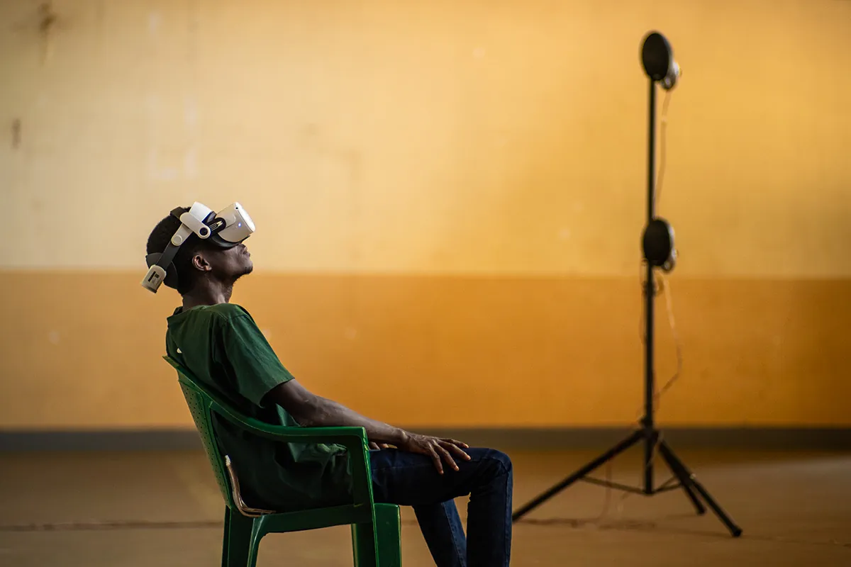 A man in a VR headset listening, seated beside a microphone stand
